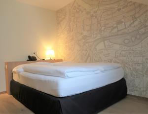 a large bed in a room with a wall at Kreuz Bern Modern City Hotel in Bern