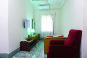 Hotel Golden Inn Chattagram Ltd في شيتاغونغ: غرفة معيشة مع أريكة حمراء وكرسي احمر