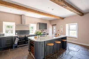 a kitchen with a large island with stools at Meadow Barn in Rishworth +38 photos