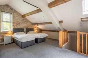 two beds in a room with a brick wall at Meadow Barn in Rishworth
