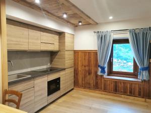 eine Küche mit Holzschränken und einem Fenster in der Unterkunft Cesa da Riz in Colle Santa Lucia