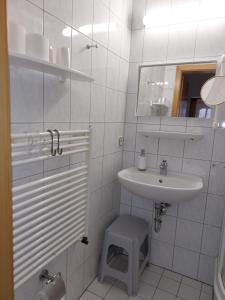 a white bathroom with a sink and a stool at Mini-1-Raum-Apartment mit eigenem Eingang in Bad Doberan