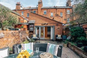 d'une terrasse avec une table et des chaises devant un bâtiment en briques. dans l'établissement Henley Gardens, à Henley-on-Thames