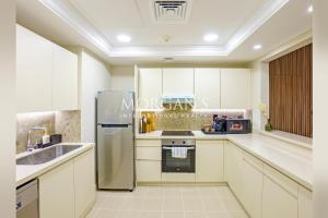 a kitchen with white cabinets and a stainless steel refrigerator at Luxury 2 bedrooms apartment in fairmont residences in Dubai