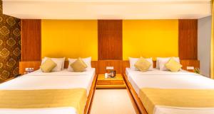 2 camas en una habitación de hotel con paredes amarillas en Shamrock Greens by Jardin Hotels en Dharmpura