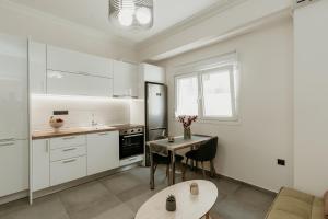 塞薩羅尼基的住宿－Urban Elegance in Thessaloniki，厨房配有白色橱柜和桌椅