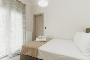 Un dormitorio blanco con una cama con toallas. en Urban Elegance in Thessaloniki, en Tesalónica