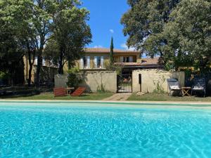 - une piscine en face d'une maison dans l'établissement Logis La Bastide De Grignan Hotel & Restaurant "La Chênaie", à Grignan