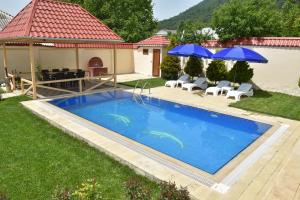 een zwembad in een tuin met twee parasols bij Foothills Villa in Gabala