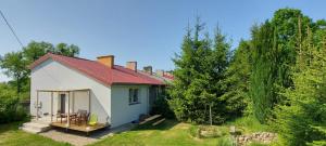 a small white cottage in a yard with trees at Domek nad jeziorem in Koszajny +6 photos