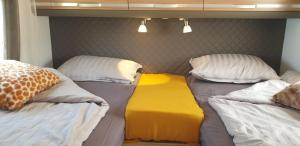 a room with two beds with pillows and a yellow mattress at Camper Relax in Murter Slanica beach - with clima in Tisno