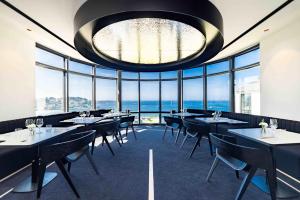 a restaurant with tables and chairs and a large chandelier at L'Agapa Hôtel - Spa Codage in Perros-Guirec