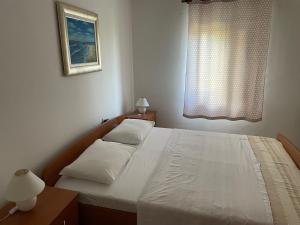 a bedroom with a bed with two pillows and a window at Holiday home Noeli & Diego in Karlobag