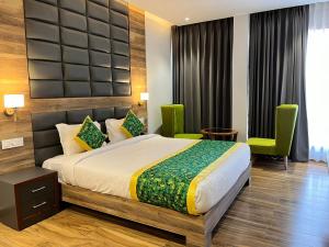 a bedroom with a bed and two green chairs at Hotel Tamarind Tree in Kharar