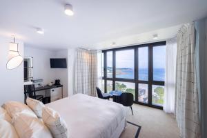 a bedroom with a bed and a desk and a window at L'Agapa Hôtel - Spa Codage in Perros-Guirec