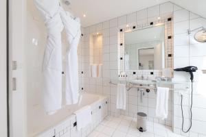 a white bathroom with a tub and a sink at L'Agapa Hôtel - Spa Codage in Perros-Guirec