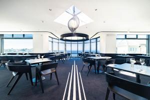 a dining room with tables and chairs and windows at L'Agapa Hôtel - Spa Codage in Perros-Guirec