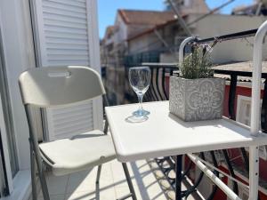 a white table and chairs on a balcony with a wine glass at GnA Place in Zakynthos Town