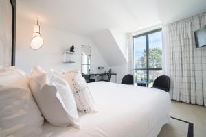 a white bedroom with a white bed with white pillows at L'Agapa Hôtel - Spa Codage in Perros-Guirec