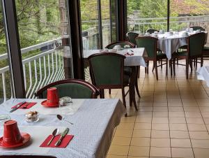 uma sala de jantar com mesas, cadeiras e janelas em Auberge Audressein em Audressein