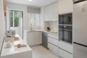 une cuisine blanche avec des armoires et des appareils blancs dans l'établissement Barreiros III by An Island Apart, à Funchal