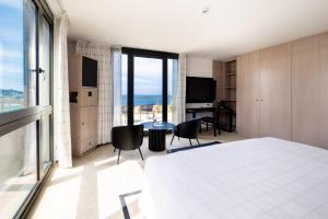- une chambre avec un lit, une table et des chaises dans l'établissement L'Agapa Hôtel - Spa Codage, à Perros-Guirec