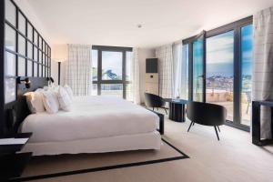 a bedroom with a white bed and a desk with chairs at L'Agapa Hôtel - Spa Codage in Perros-Guirec