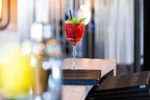 a red drink in a glass sitting on a table at L'Agapa Hôtel - Spa Codage in Perros-Guirec