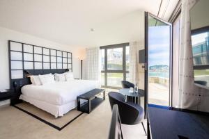 a bedroom with a white bed and a large window at L'Agapa Hôtel - Spa Codage in Perros-Guirec