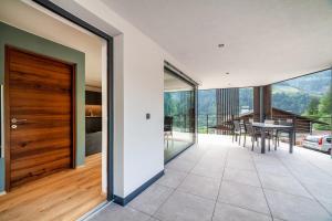 an open living room with a wooden door and a table at Aktiv Lodge Meran - Terrace One in Saltusio +25 photos