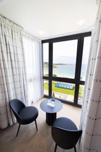 a room with a table and chairs and a large window at L'Agapa Hôtel - Spa Codage in Perros-Guirec