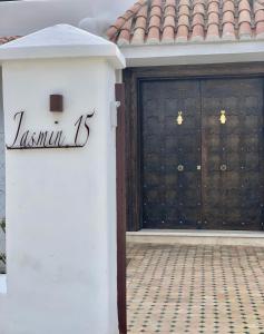eine Garage mit einer schwarzen Tür und einer weißen Wand in der Unterkunft Villa Jasmin 15 in Mʼdik