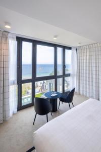 a hotel room with a bed and a table and chairs at L'Agapa Hôtel - Spa Codage in Perros-Guirec