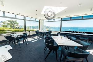 a restaurant with tables and chairs and large windows at L'Agapa Hôtel - Spa Codage in Perros-Guirec