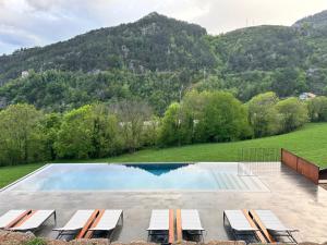 uma piscina com cadeiras e montanhas ao fundo em Hotel Rural-Spa Resguard Dels Vents em Ribes de Freser