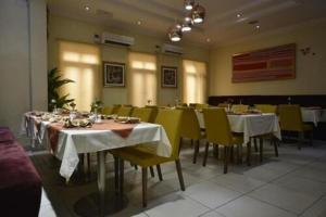 uma sala de jantar com mesas brancas e cadeiras amarelas em Palazzo Dumont Hotel em Ikuata