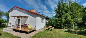 a small white house with a table and chairs at Domek nad jeziorem in Koszajny