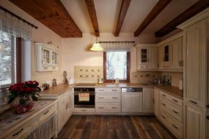 a large kitchen with white cabinets and wooden floors at Przytulia willa in Stryszawa