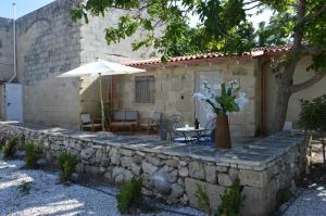 a stone retaining wall with a table and an umbrella at Corte Soleto 22 in Martano