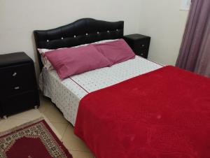 a bedroom with a bed with a red blanket and two night stands at caprice appartement in Ifrane