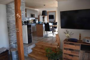 a living room with a large television and a kitchen at Ferienhaus AlpenBlick in Schöfweg