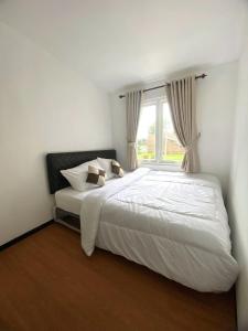 a bedroom with a large white bed with a window at Villa Royal Arois Syariah Dekat Jatim Park 3 in Tlekung