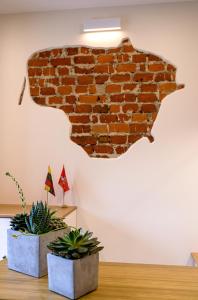 eine Ziegelwand mit zwei Topfpflanzen auf einem Tisch in der Unterkunft Klaipeda Hostel in Klaipėda