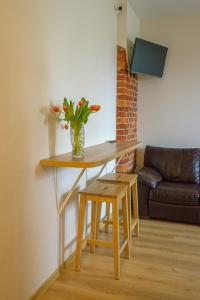 a table and stool with a vase of flowers on it at Klaipeda Hostel in Klaipėda