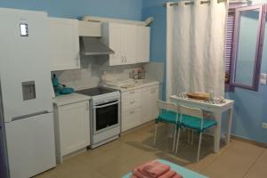 a kitchen with white appliances and a table and chairs at Vourkari Studio with full kitchen in Ioulis
