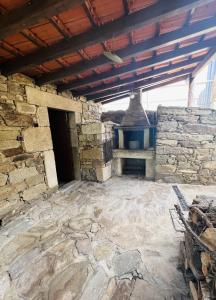 an outdoor room with a stone fireplace in a building at Casa do Riacho - Douro in Armamar