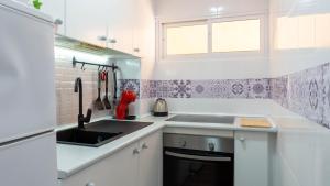 une petite cuisine blanche avec un évier et une cuisinière dans l'établissement Home Corinto Beach terraza y piscina - Benalmadena Malaga, à Benalmádena