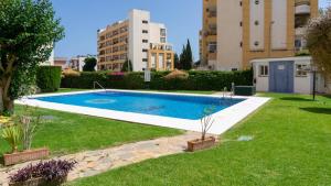 une piscine dans une cour avec des bâtiments en arrière-plan dans l'établissement Home Corinto Beach terraza y piscina - Benalmadena Malaga, à Benalmádena