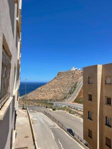 an empty street in front of a building and the ocean at PROMO Appartement Familial avec WiFi in Al Hoceïma