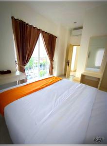 a large white bed in a room with a window at Batik Oma House in Jetis